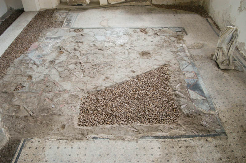 a tile floor, partially restored, surrounded by a mosaic