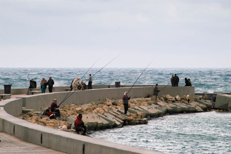 men fishing off the promontory and stone breakers