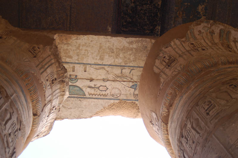 Brightly painted heiroglyphs on the ceiling between the pillars