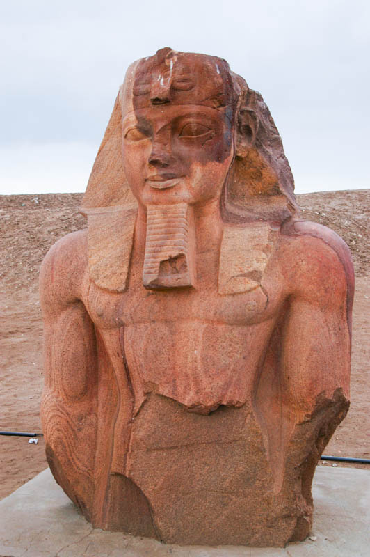 A matching red-granite statue, partially standing
