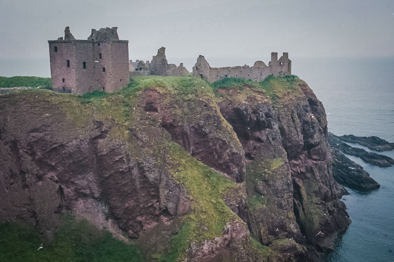 the castle is strongly defended by cliffs, seen from across the bay